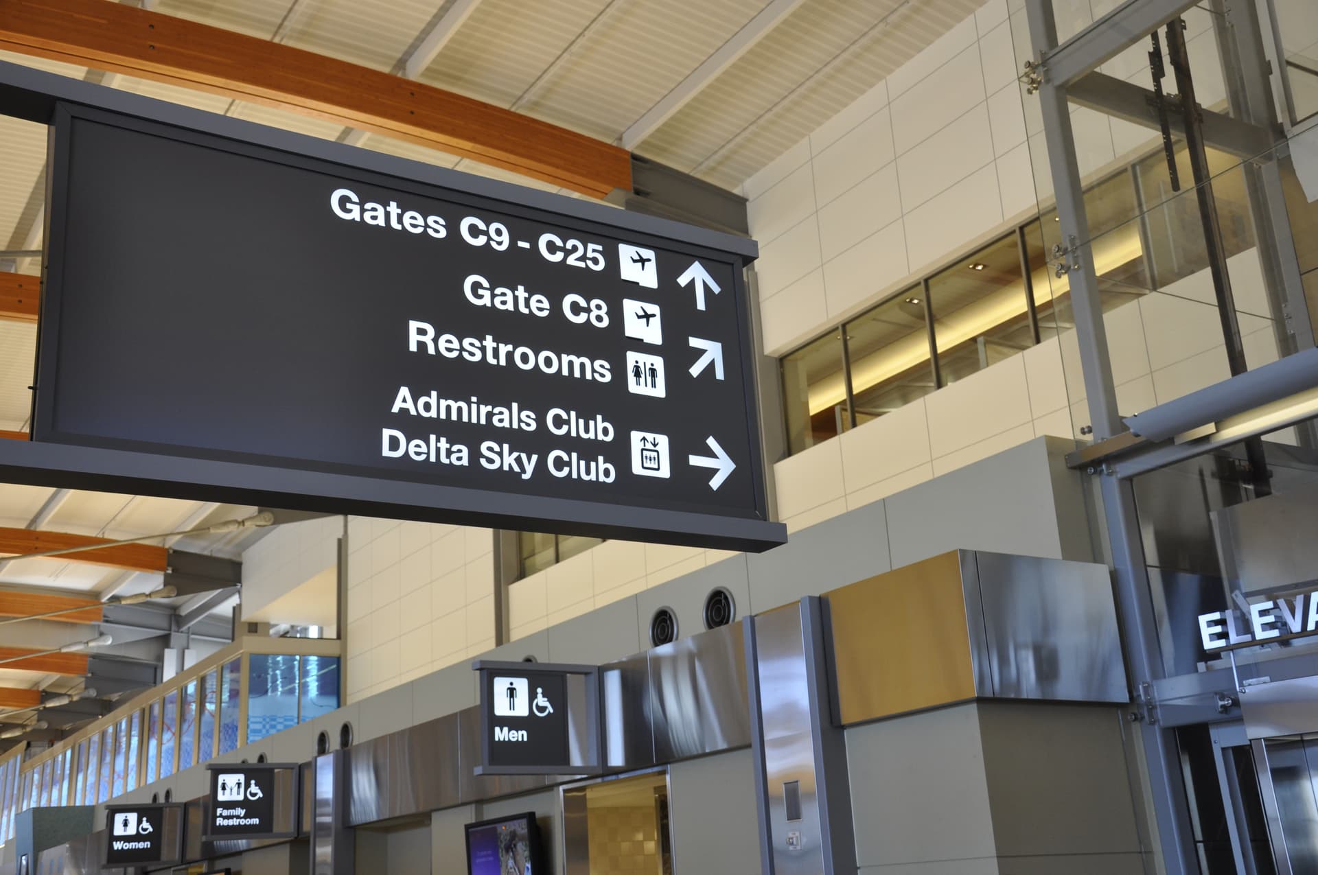 Airport directional sign showing gates C9-C25, Gate C8, restrooms, Admirals Club and Delta Sky Club with arrows.